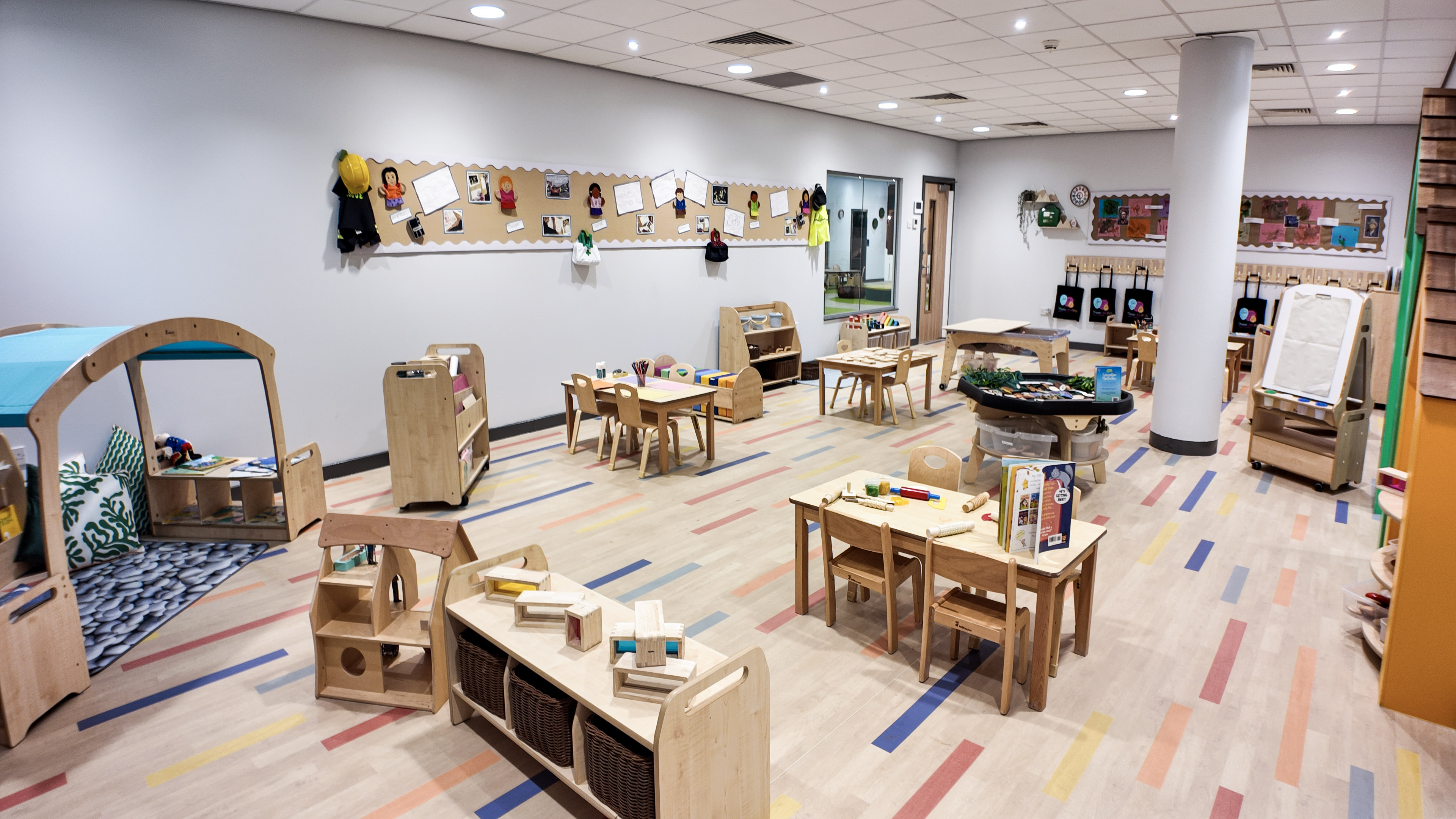 Classroom with art tables, drawing rack and cubby hooks