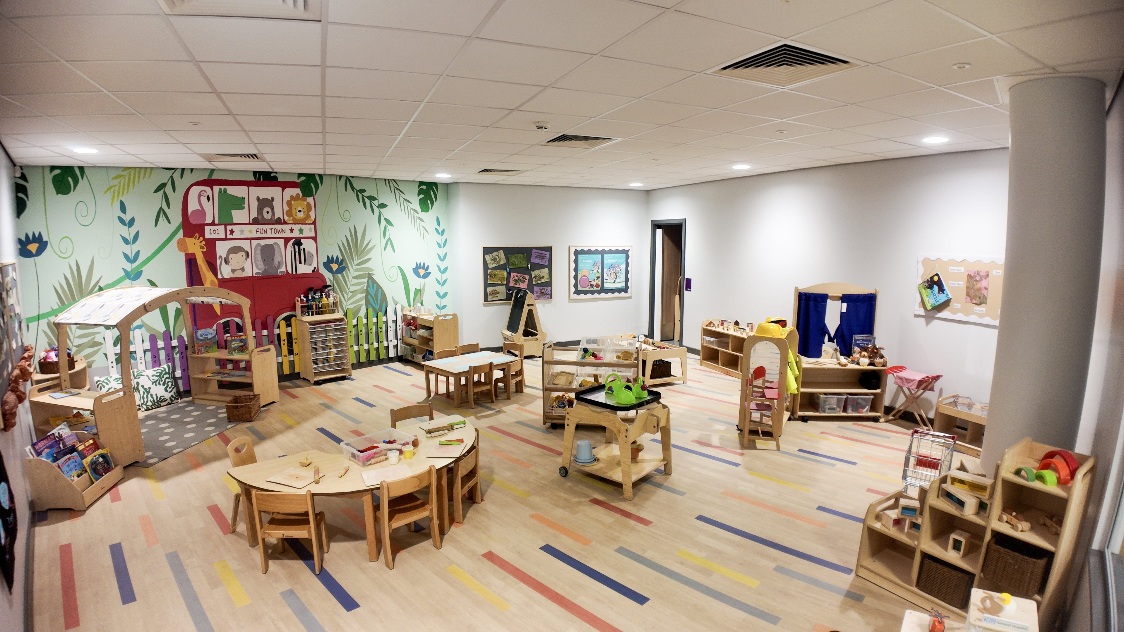Toddler room with Fun Town mural, play kitchen and low activity tables